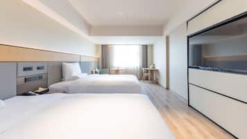A hotel room with two beds, a desk, a chair, and a TV.