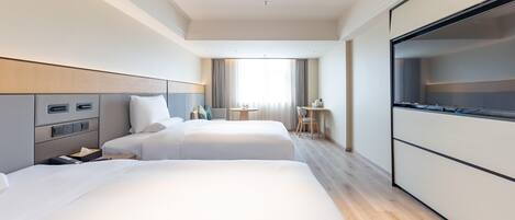 Une chambre d’hôtel avec deux lits, un bureau, une chaise et un téléviseur.