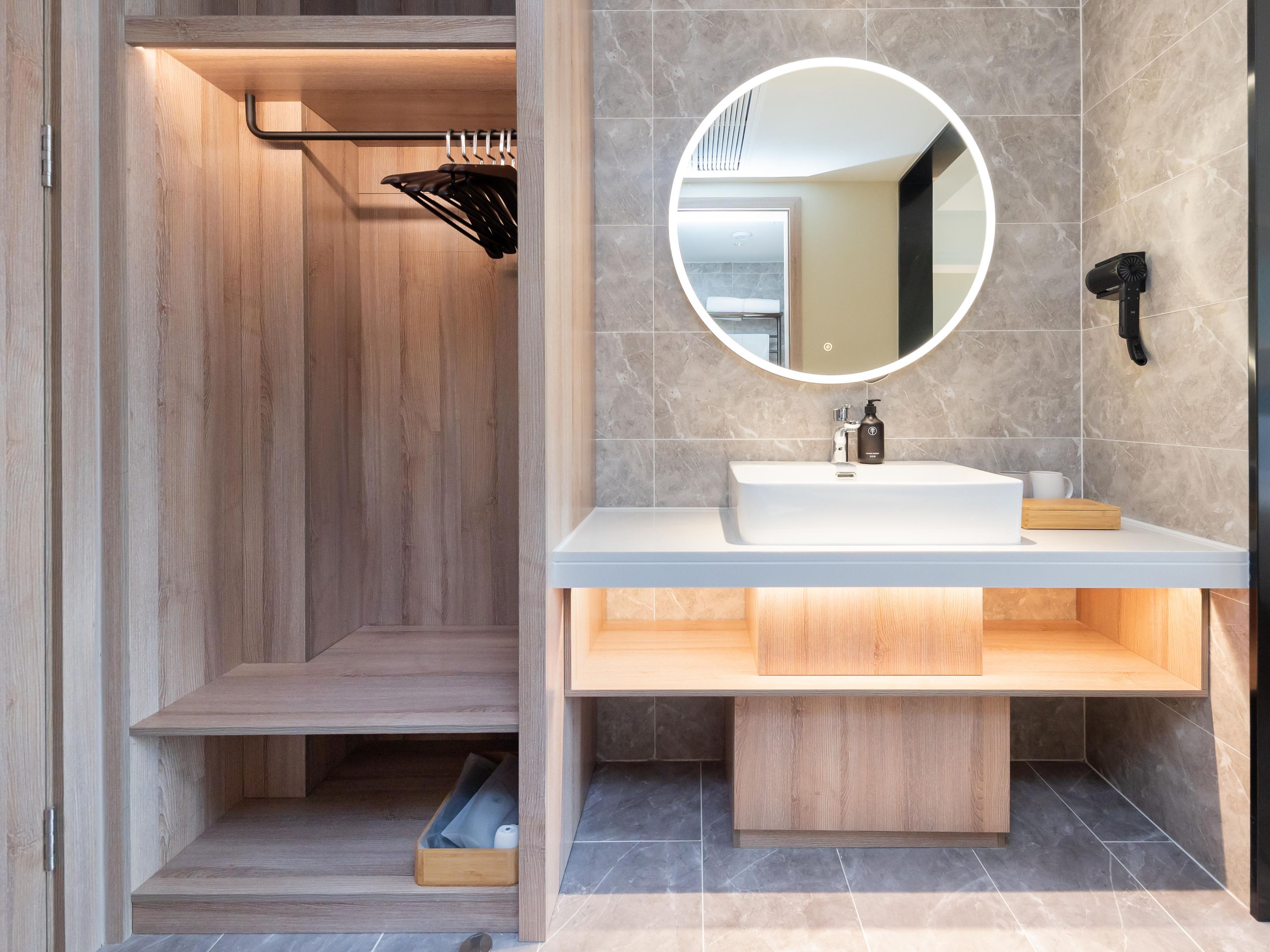 Ein modernes Badezimmer mit einer Duschkabine aus Holz, einem weißen Waschbecken mit Spiegel und einem Handtuchhalter.