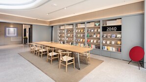 A modern library with a long wooden table and chairs, bookshelves, and a '2040 Bookstore' sign. - Ji Hotel (Suzhou)