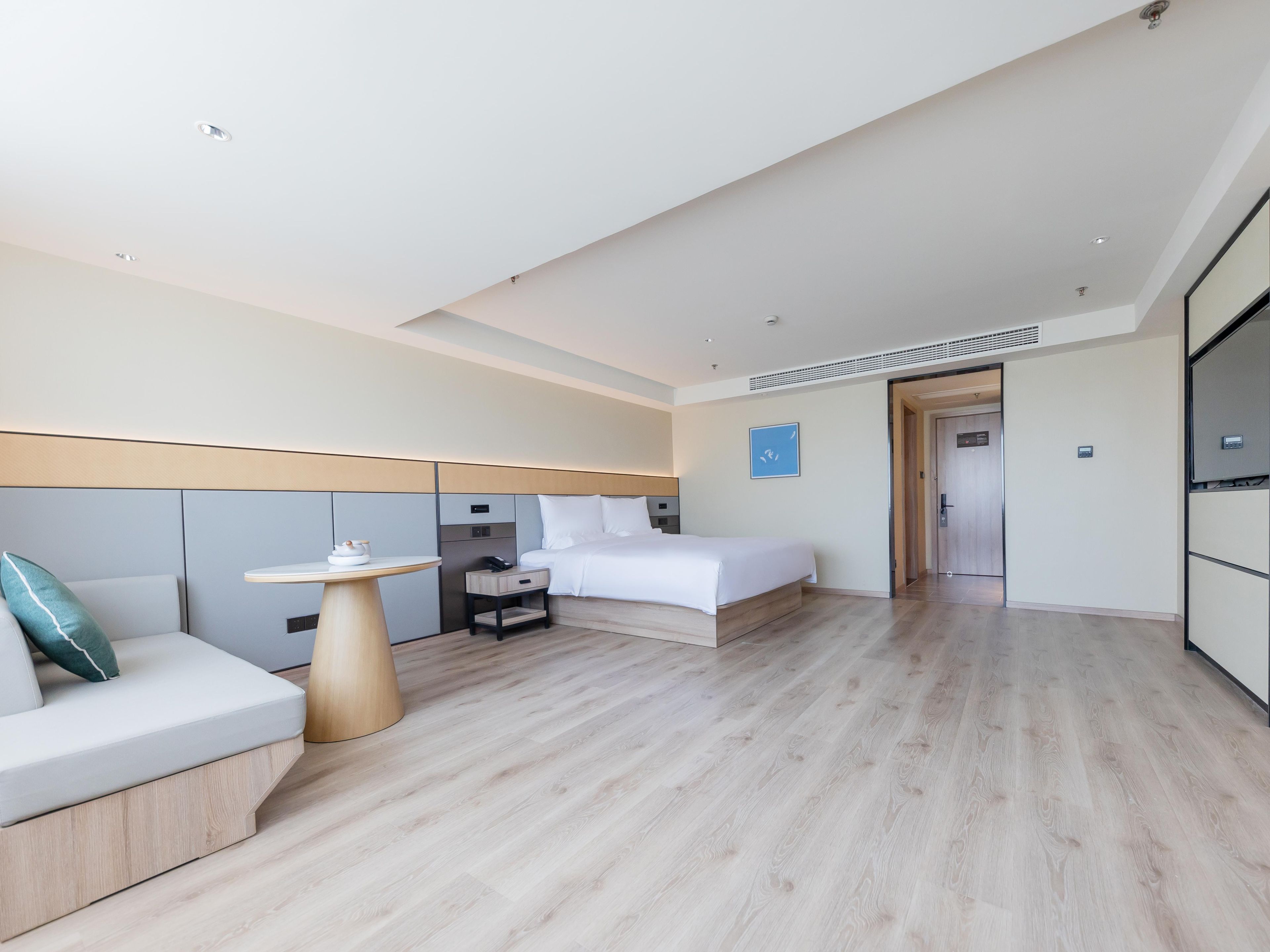 Una habitación de hotel moderna con cama, mesita de noche y zona de estar con sofá.