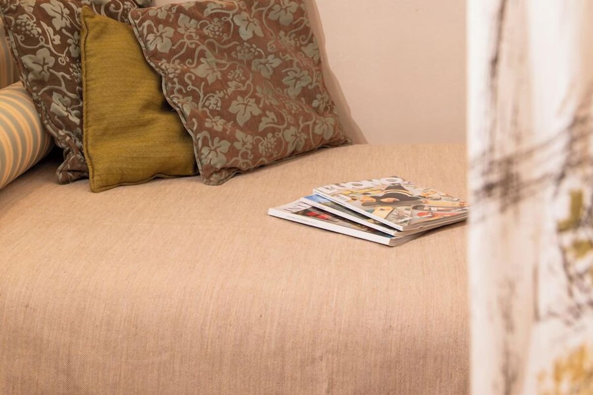 Une chambre à coucher avec un lit, des oreillers, un magazine, un miroir et un luminaire suspendu.