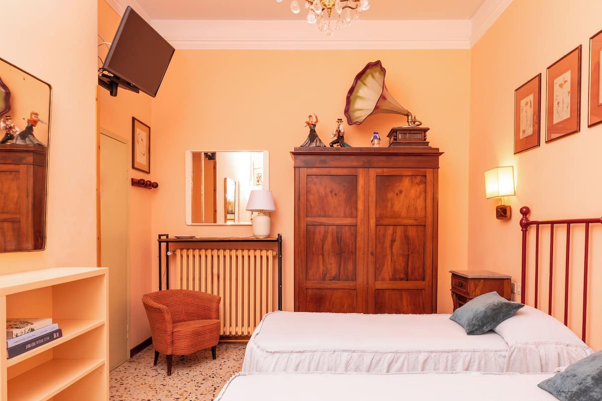 Une chambre à coucher comprenant un lit, une chaise, une commode, un radiateur et des lampes fixées au mur.