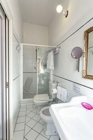 Et lille badeværelse med bruser, toilet og håndvask.
