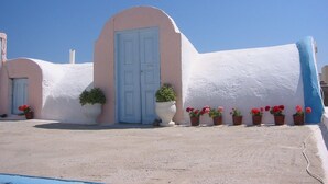 Un edificio con fachada blanca, puerta azul y plantas en macetas.