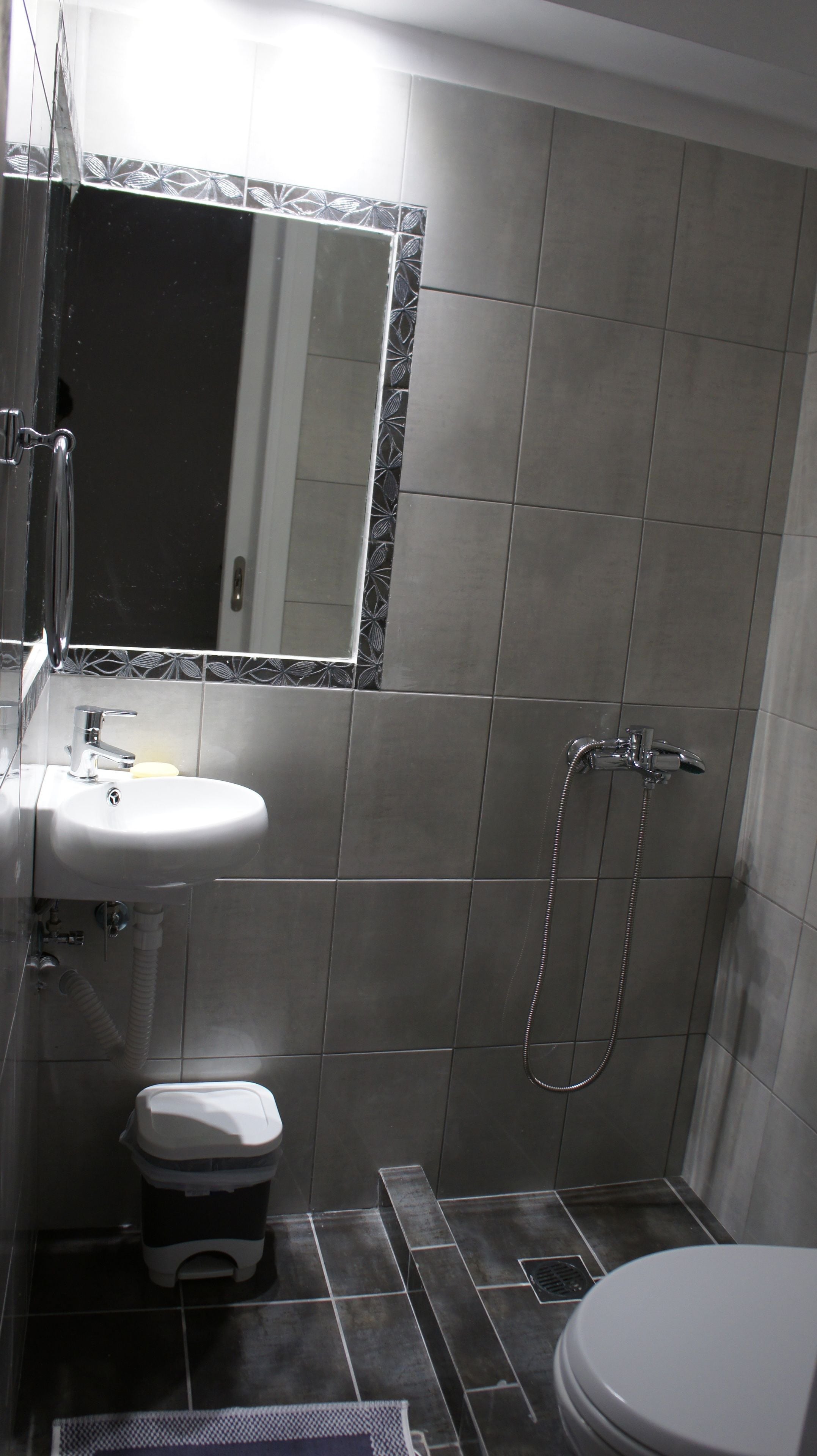 A bathroom with a sink, mirror, toilet, and shower.