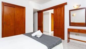 A hotel room with a bed, a bedside table, a mirror, and wooden wardrobes.
