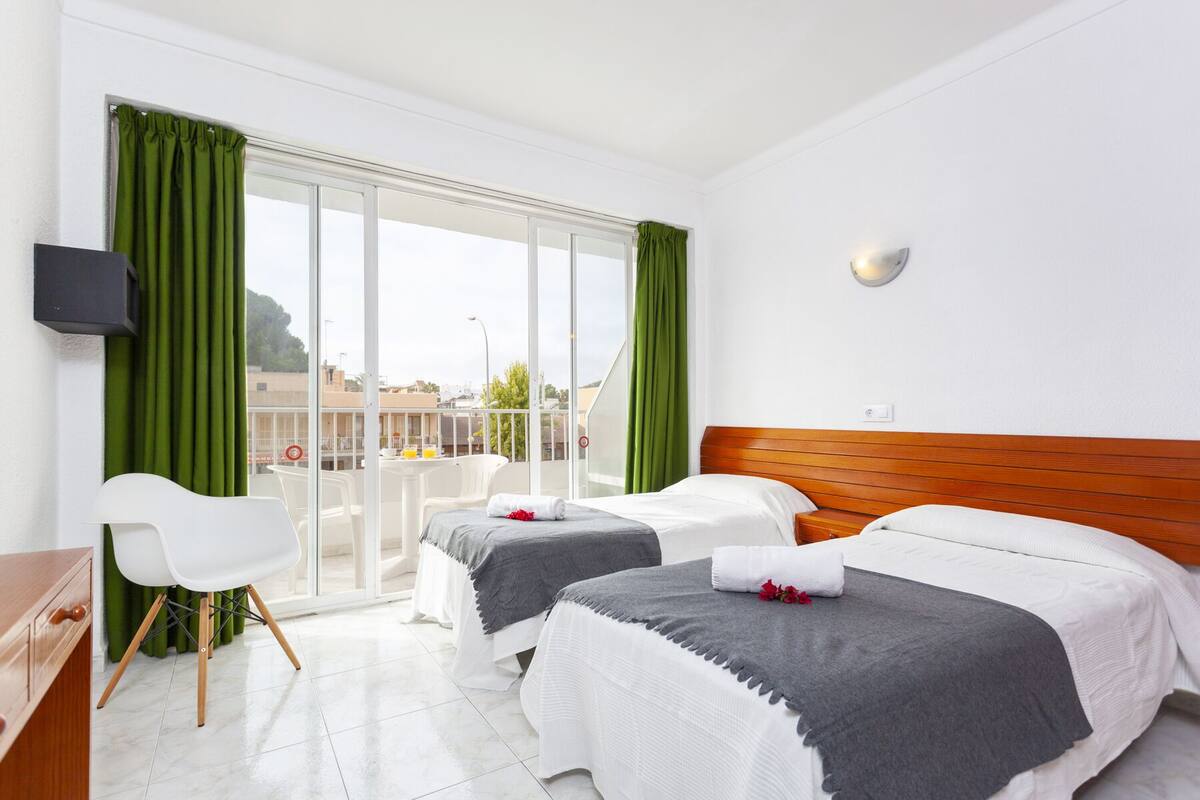 Una habitación de hotel con dos camas, un escritorio, una silla y un televisor.