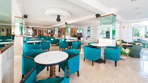 A spacious hotel lobby with multiple seating areas, a bar, and a television screen.