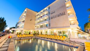 A hotel with a pool and multiple balconies.