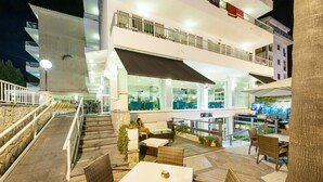 A multi-story hotel with outdoor seating areas, a staircase, and a pool.