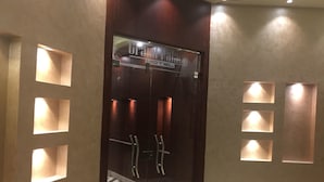 En hotellentrél med en glasdörr, vägglampor som ger ett vackert ljus och ett mönstrat golv.