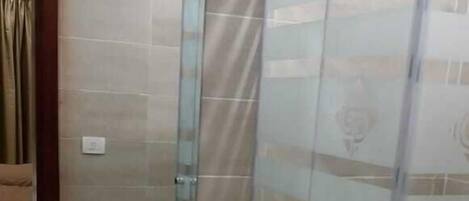 Un baño con cabina de ducha de vidrio, un lavabo y un espejo.
