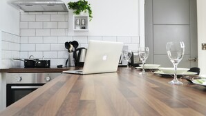 Uma cozinha moderna com bancada de madeira, coifa de aço inoxidável, um laptop e copos de vinho.