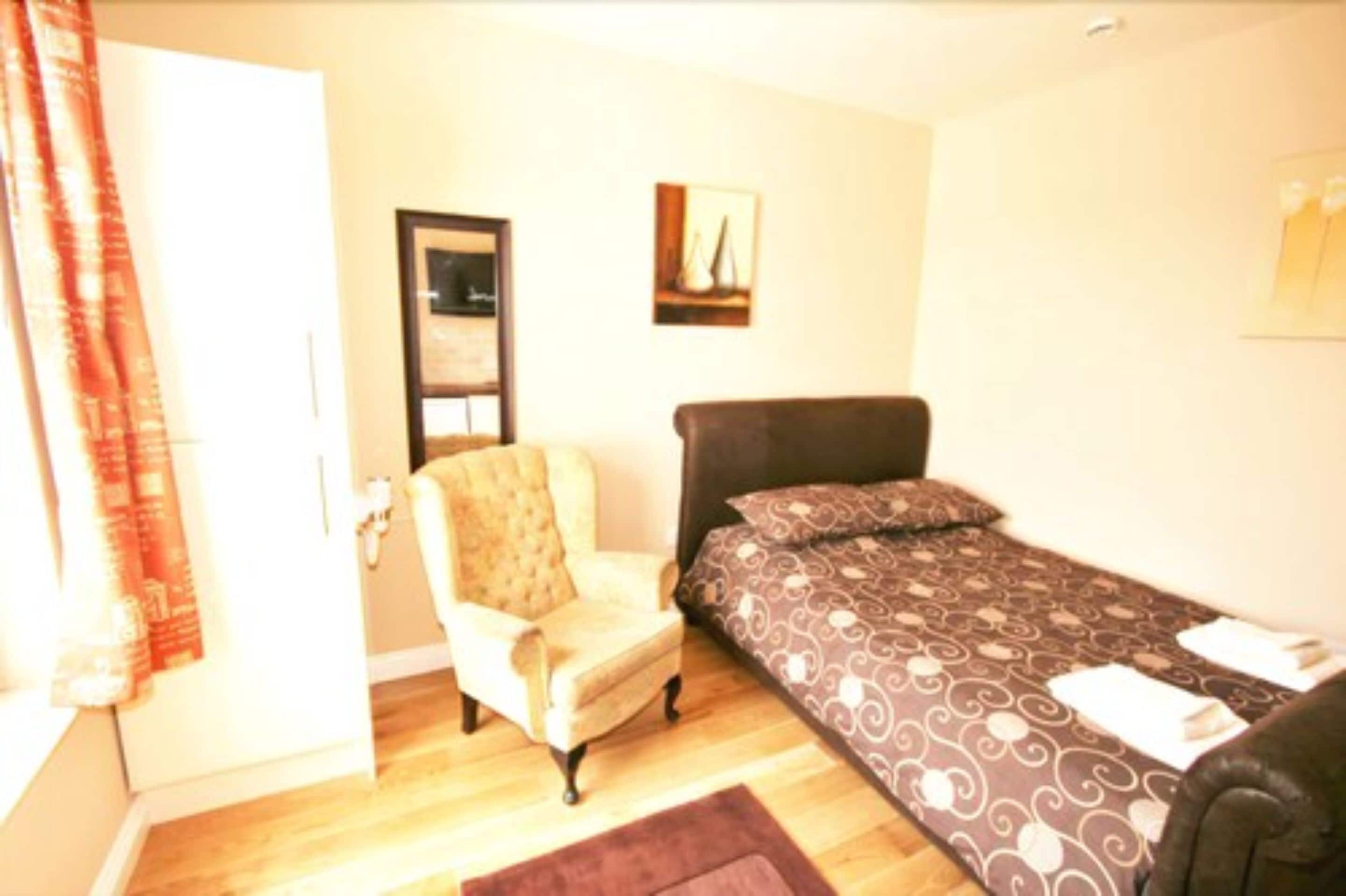 Un dormitorio con una cama, una silla y una puerta.