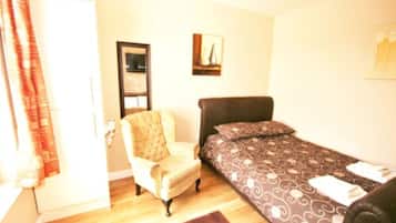 Un dormitorio con una cama, una silla y una puerta.