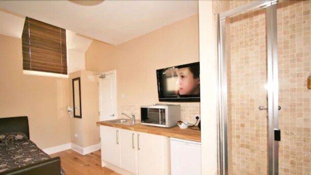 A compact kitchen with a microwave, sink, and cabinets. - Central Studios Gloucester Road by Rooms Booked - Free Parking (Cheltenham)