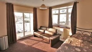 A room with a sofa, a bed, a radiator, and a window with curtains. - Central Studios Gloucester Road by Rooms Booked - Free Parking (Cheltenham)