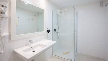 Un baño moderno con cabina de ducha de vidrio, un lavabo blanco y un espejo grande.
