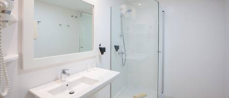 A modern bathroom with a glass-enclosed shower, a white sink, and a large mirror.