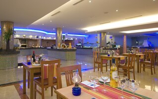 Un restaurante con zona de bar, mesas dispuestas con copas de vino y platos, y una lámpara decorativa sobre la mesa.