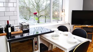 Una cocina moderna con comedor, un ventanal con vistas a árboles y un televisor.