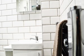 A bathroom with white tiled walls, a sink, and a mirror.