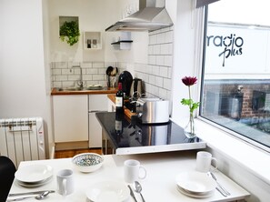 A modern kitchen with a dining area, featuring a window with a view of the city, a toaster, and a vase with a flower on the table.