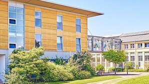 Un bâtiment moderne doté de nombreuses fenêtres et d’une pelouse bien entretenue.
