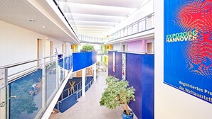 Un couloir intérieur moderne, doté de rampes en verre, d’un escalier central et d’une banderole pour l’Exposition universelle de Hanovre 2020.