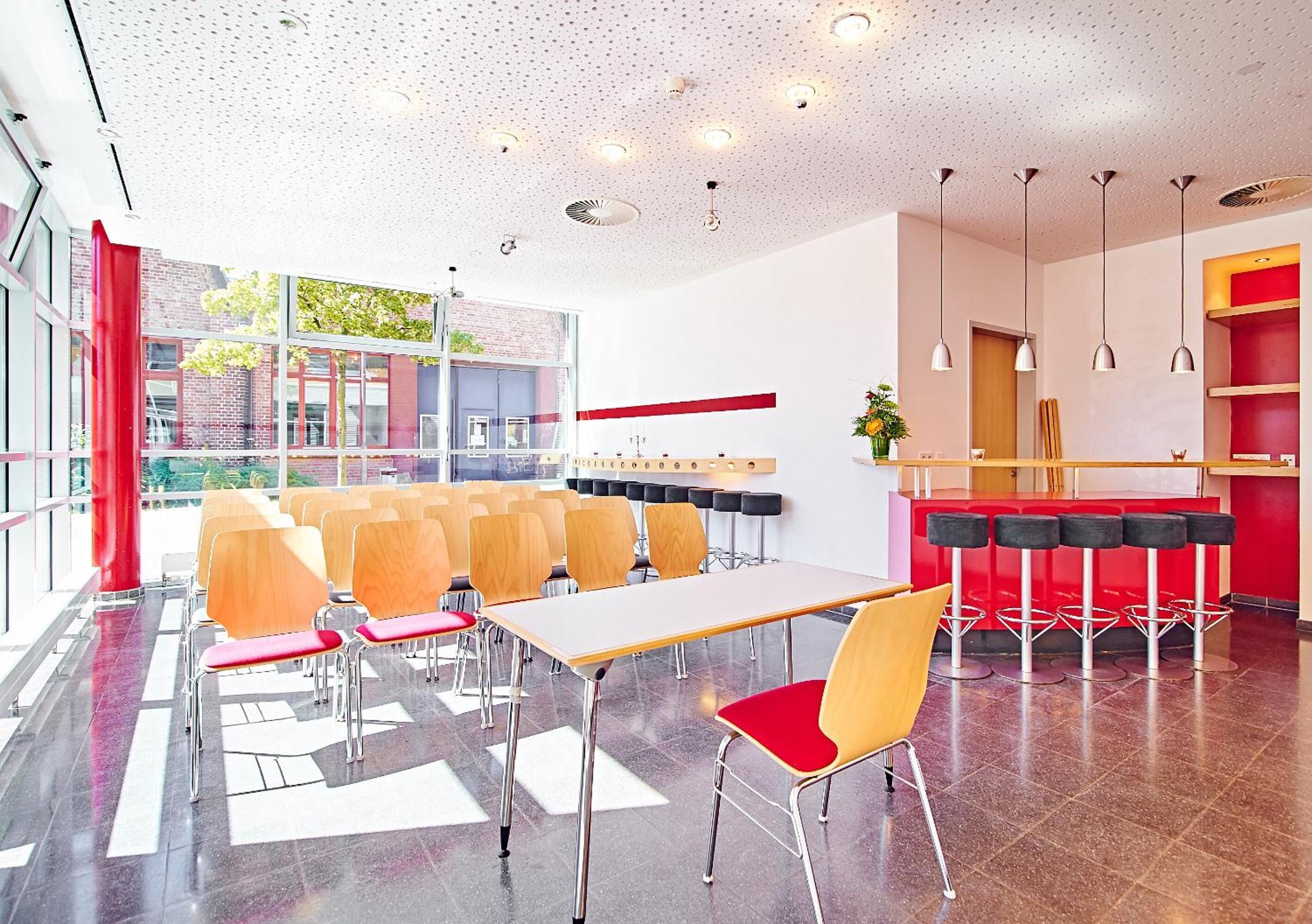Un comedor moderno con una mesa larga y sillas, una zona de bar con taburetes y vistas al exterior.