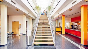 Un intérieur moderne avec un escalier central, un plafond en verre et un comptoir de couleur rouge.