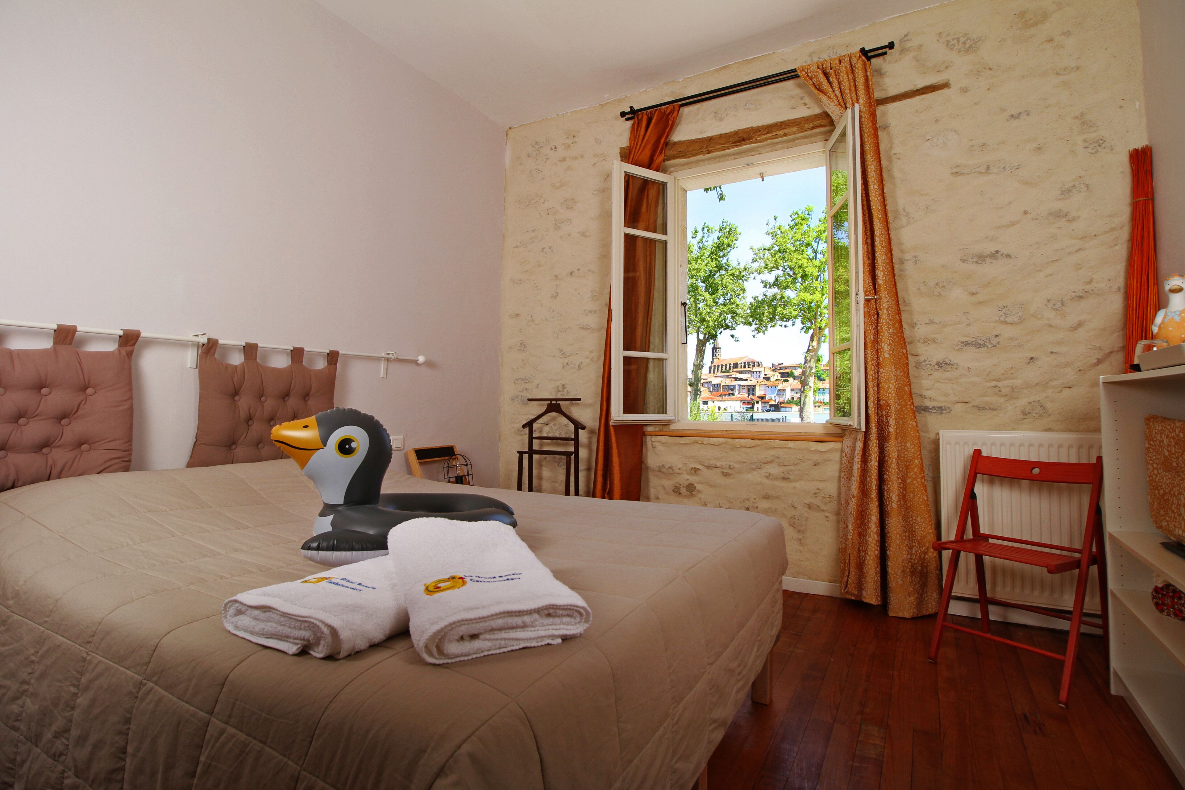 Une chambre d’hôtel avec un lit, une fenêtre avec des rideaux, un radiateur et une chaise rouge.