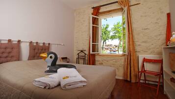 Une chambre d’hôtel avec un lit, une fenêtre avec des rideaux, un radiateur et une chaise rouge.