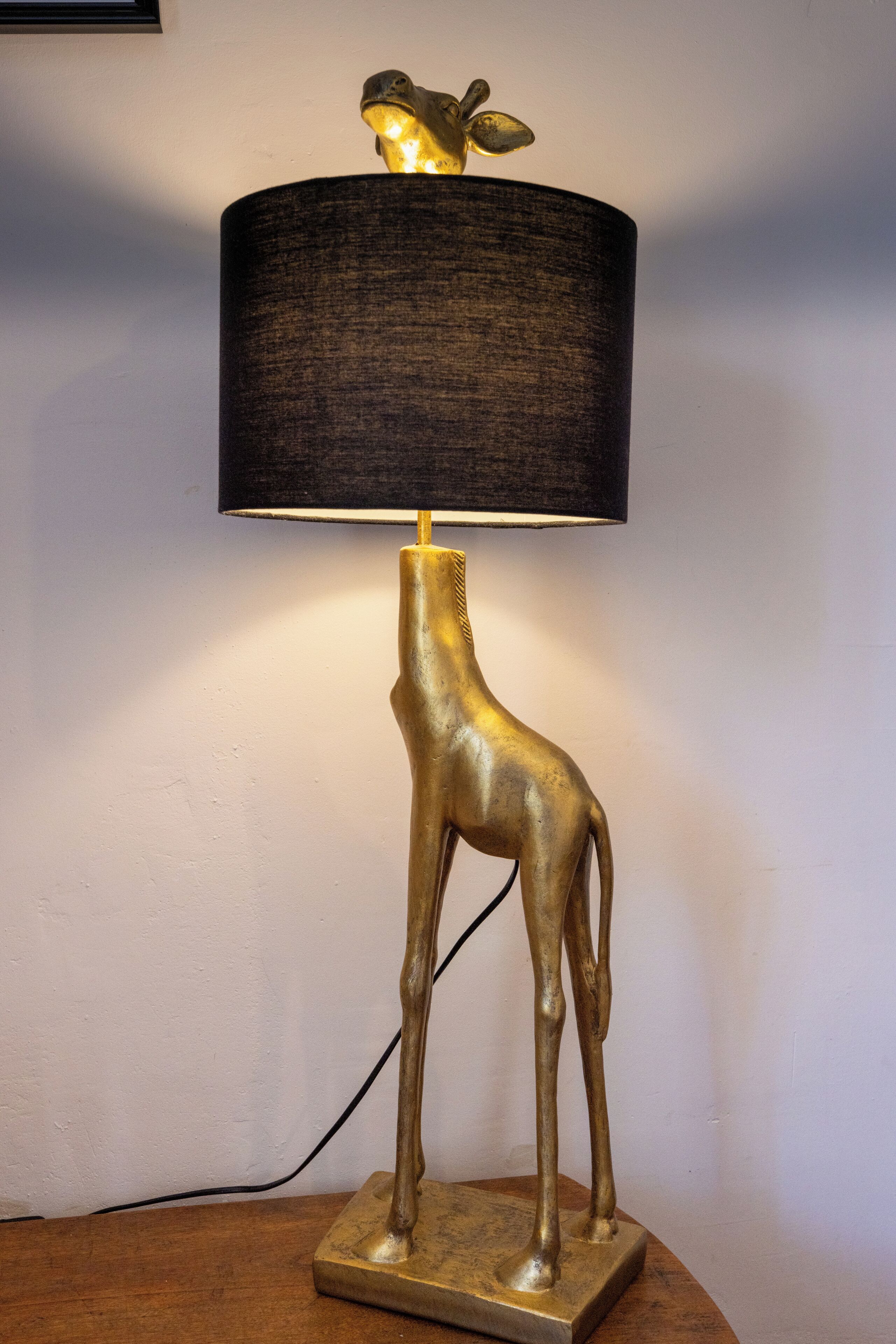 A lamp with a giraffe-shaped base and a black lampshade.
