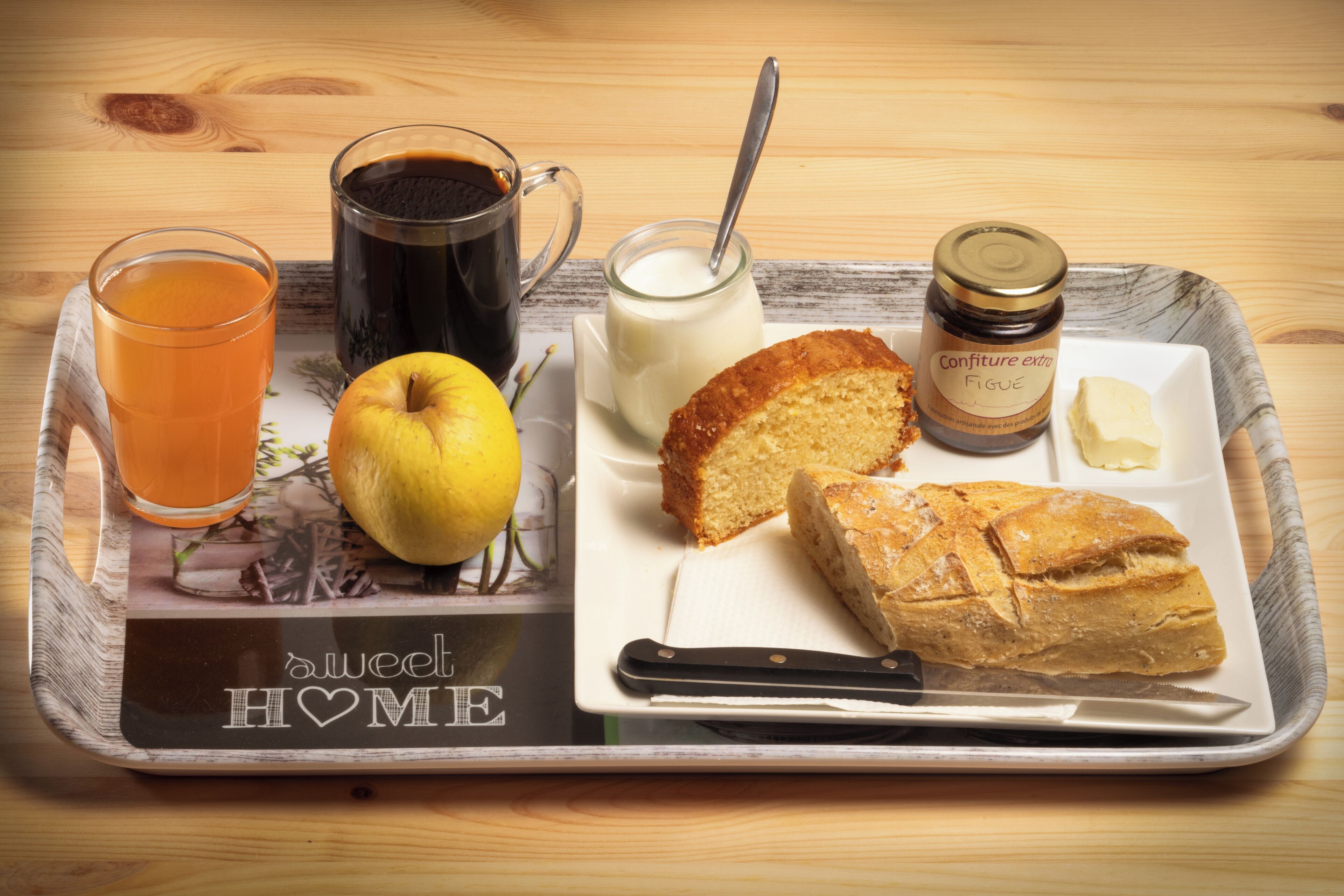A tray with a slice of cake, a knife, a glass of orange juice, a cup of coffee, a glass of milk, and a lemon.