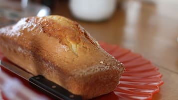 A loaf of bread on a red plate with a knife beside it.