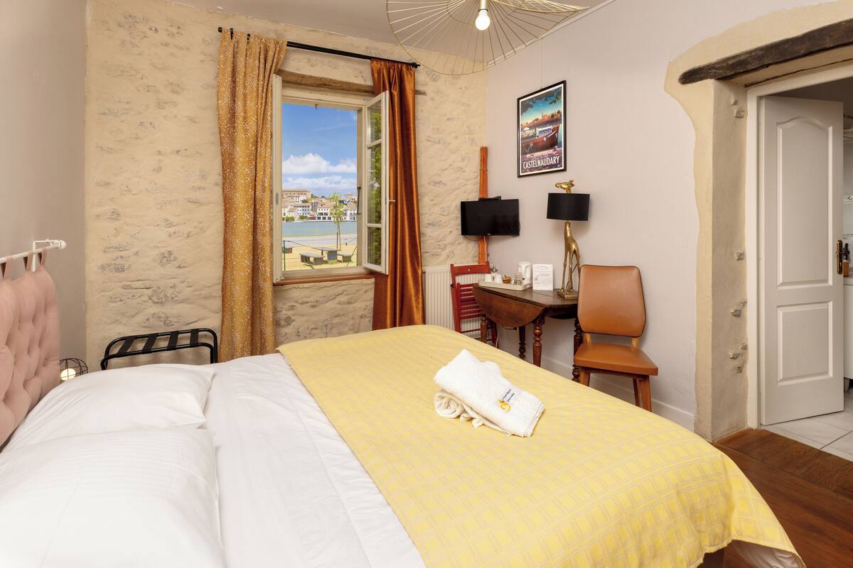 A hotel room with a bed, a desk, a chair, a television, and a window with a view.