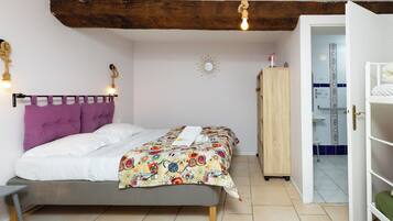 Un dormitorio con una cama, cabecera de madera, un armario y un baño visible a través de una puerta abierta.