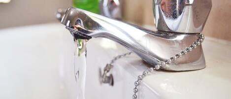 A chrome faucet with water running, attached to a white sink.