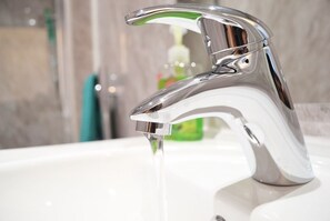 A modern bathroom with a chrome faucet and clear running water. - TwentyThree (Coventry)