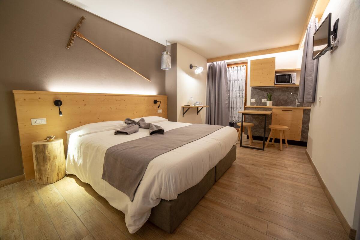 A compact bedroom with a bed, bedside table, and a small kitchenette area.