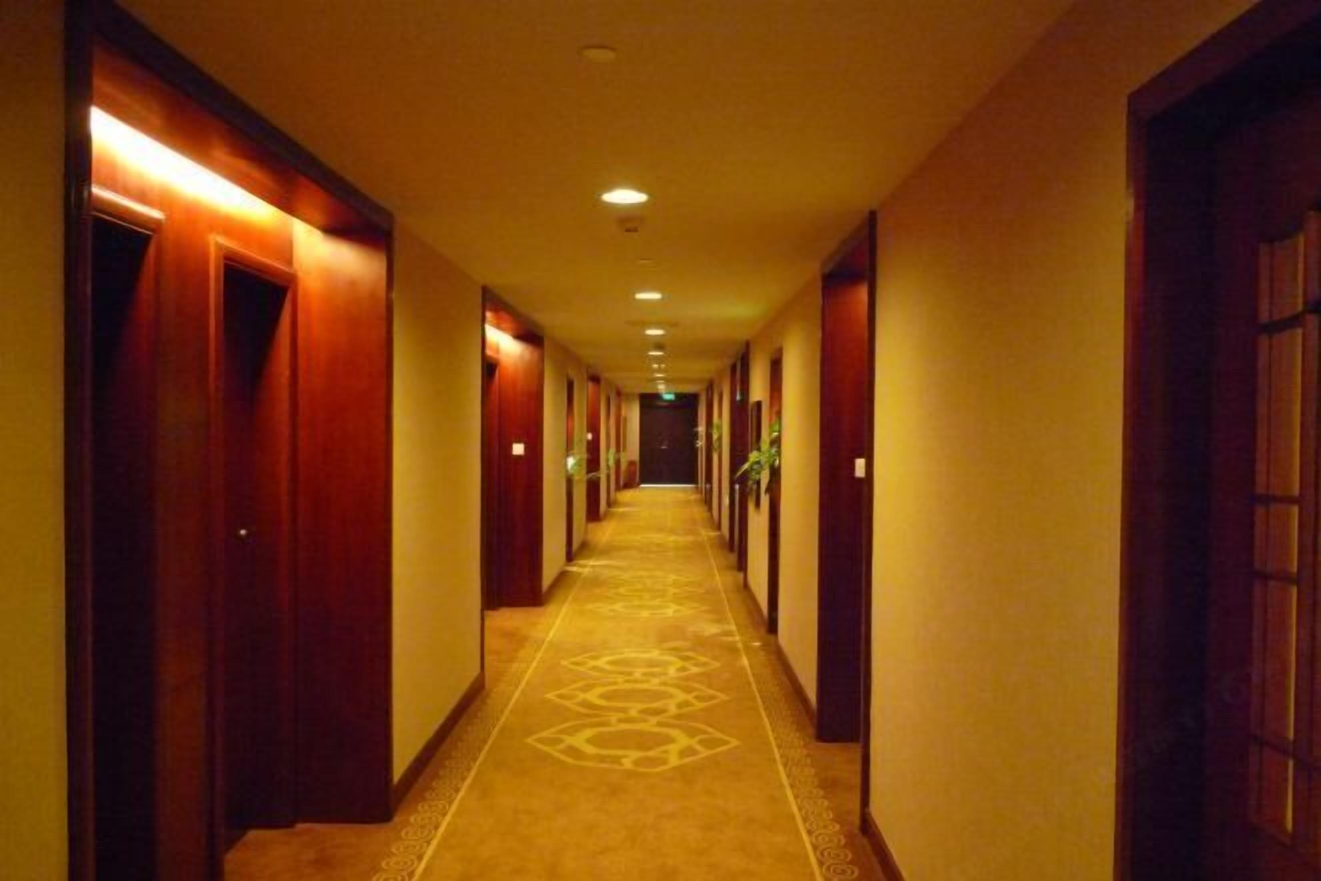 A hotel hallway with wooden doors and a carpeted floor.