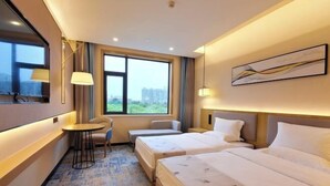 A hotel room with two beds, a small table, a chair, a window with a view, and a painting on the wall. - Zhongtian Huanghai Hotel (Rudong)