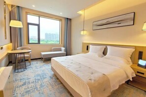 A hotel room with a bed, a desk, a chair, a window with a view, and a painting on the wall.