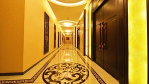 A long, well-lit hallway with a decorative floor pattern, leading to a dark wooden door at the end. - Zhongtian Huanghai Hotel (Rudong)