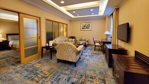 A hotel room with a bed, a sofa, a coffee table, a TV, and a desk. - Zhongtian Huanghai Hotel (Rudong)