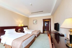 A hotel room with two beds, a desk, a television, and a door leading to another room. - Zhongtian Huanghai Hotel (Rudong)