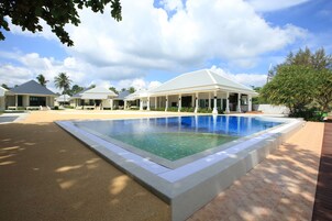 Una piscina al aire libre, sombrillas, sillones reclinables de piscina