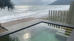 Vista despejada de una piscina con cubierta de madera y vista al océano.
